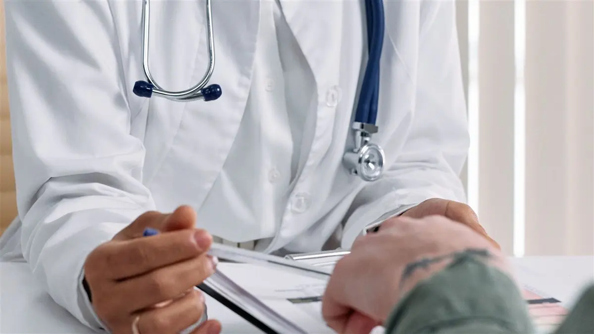 Doctor pointing at an anatomical diagram of the male urinary system during a consultation