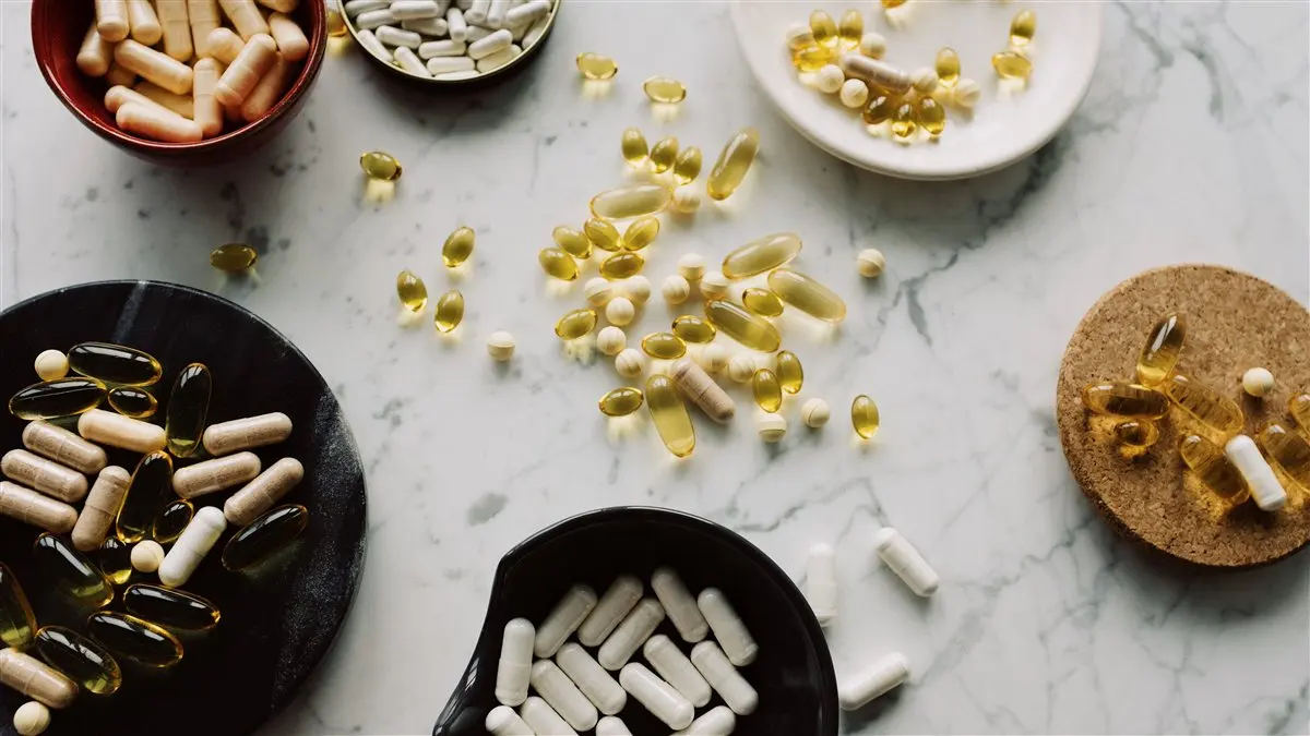 Saw palmetto berries and softgel capsules arranged on a wooden table next to a research journal